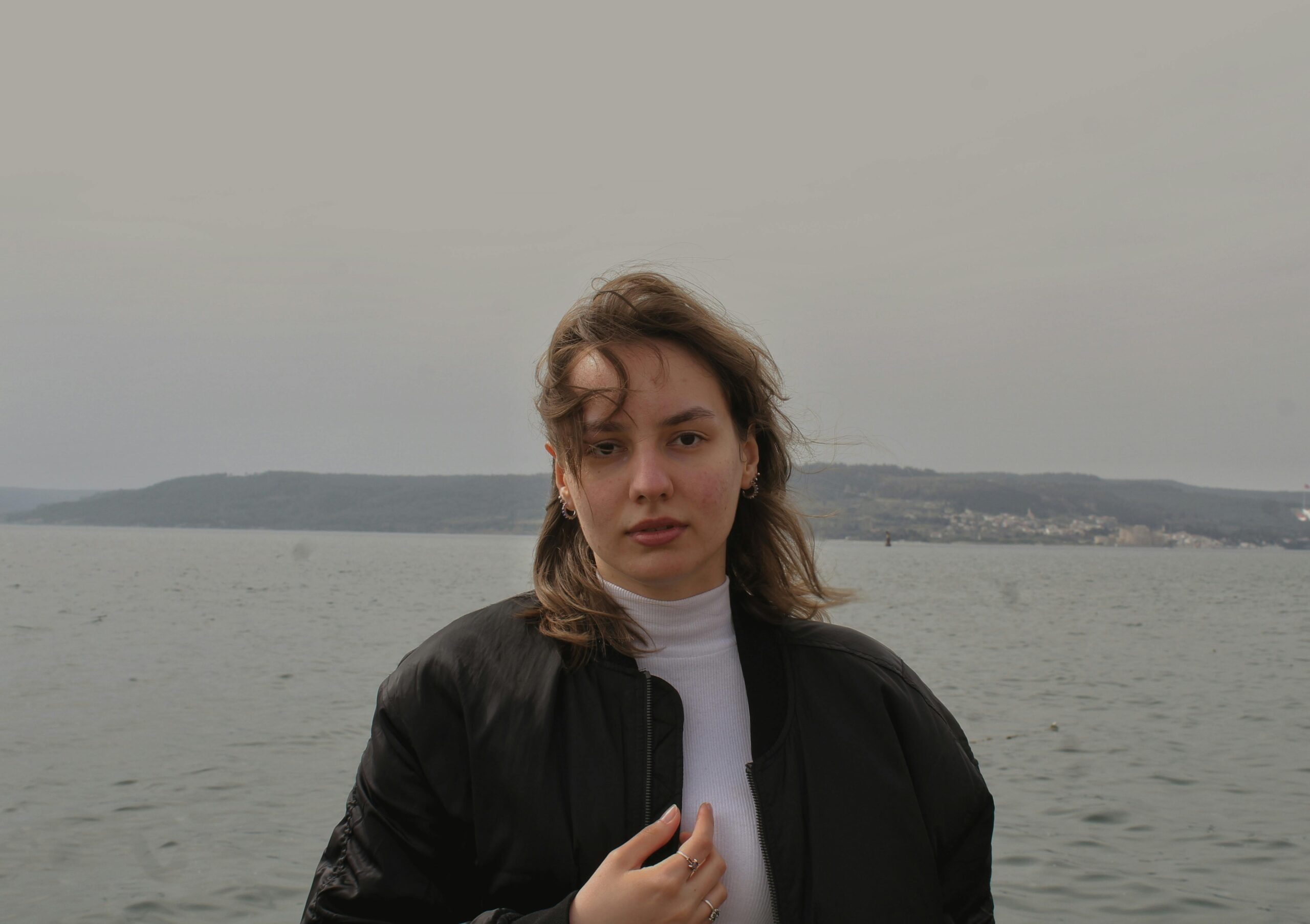 Outdoor portrait of a woman by the sea on a gray, windy day in Çanakkale, Turkey.